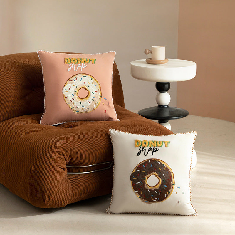 Square decorative cushion with embroidered donut motif and decorative piping edge