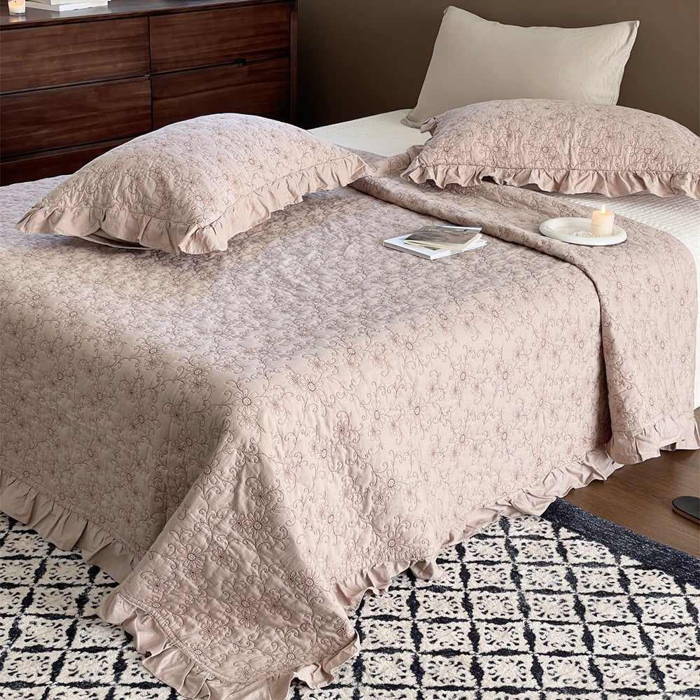Padded quilted bedspread with a floral all-over pattern and ruffled edges
