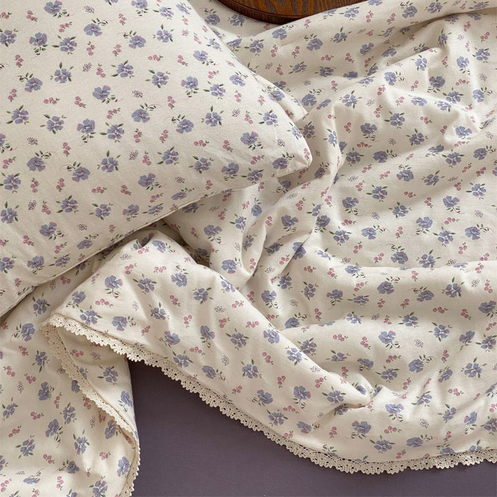 Quilted throw blanket made of cotton blend with delicate floral pattern and lace edge